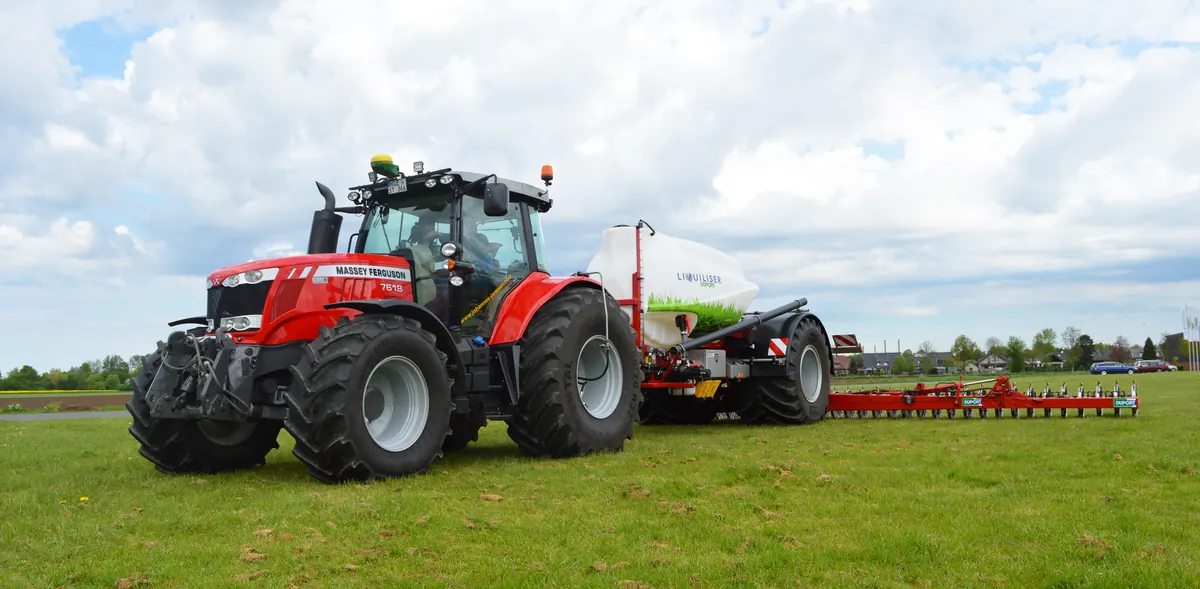 Roter Massey-Ferguson-Traktor mit weißem Liquiliser-Tank und rotem Anbaugerät von Duport auf einer Wiese.