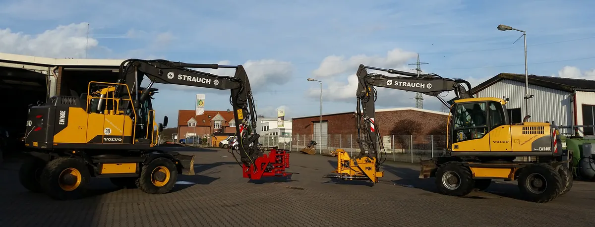 Zwei gelbe Volvo-Mobilbagger mit der Aufschrift Strauch auf einem gepflasterten Hof.