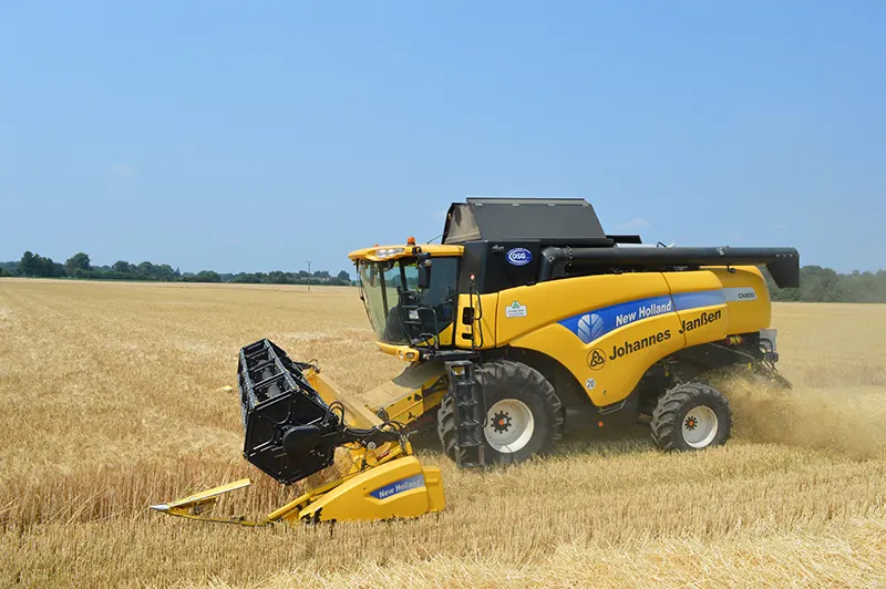 Gelber Mähdrescher von New Holland beim Dreschen in einem reifen Getreidefeld.