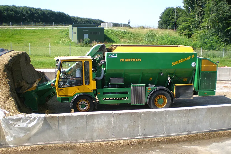 Grün-gelber selbstfahrender Futtermischwagen Marmix Superchamp nimmt Futter am Fahrsilo auf.